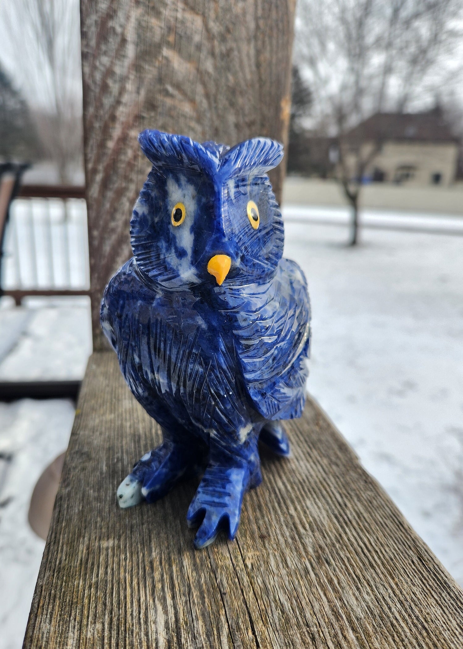 May include: A blue lapis lazuli owl figurine with yellow eyes. The owl is carved with intricate details and has a textured surface.