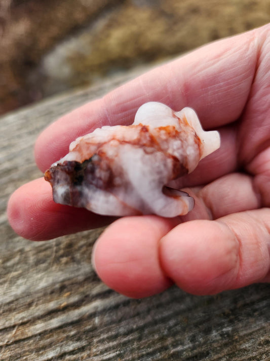 May include: A white and red agate carved into the shape of a frog.