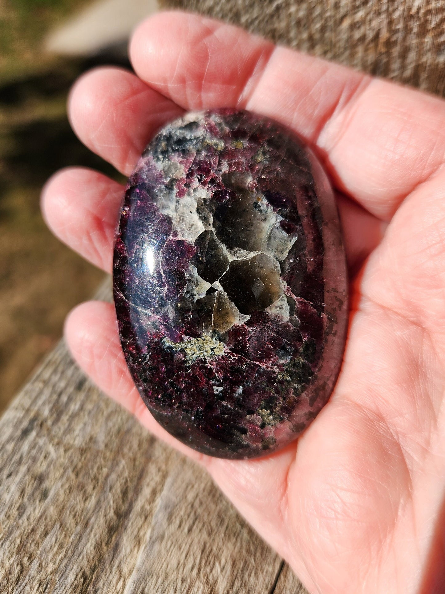 May include: A smooth, oval-shaped, polished stone with a dark red, black, and white marbled pattern. The stone has a glossy finish.