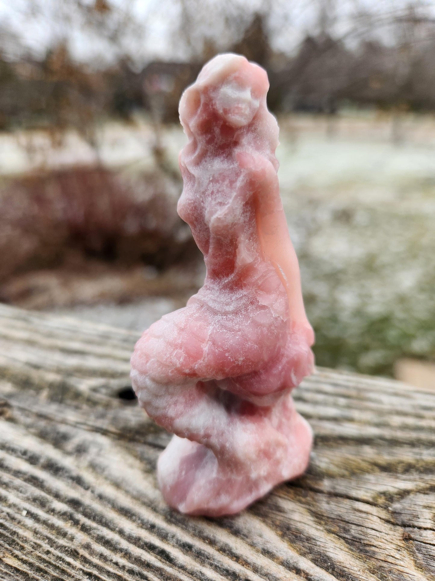 May include: A pink and white carved mermaid figurine made of stone.