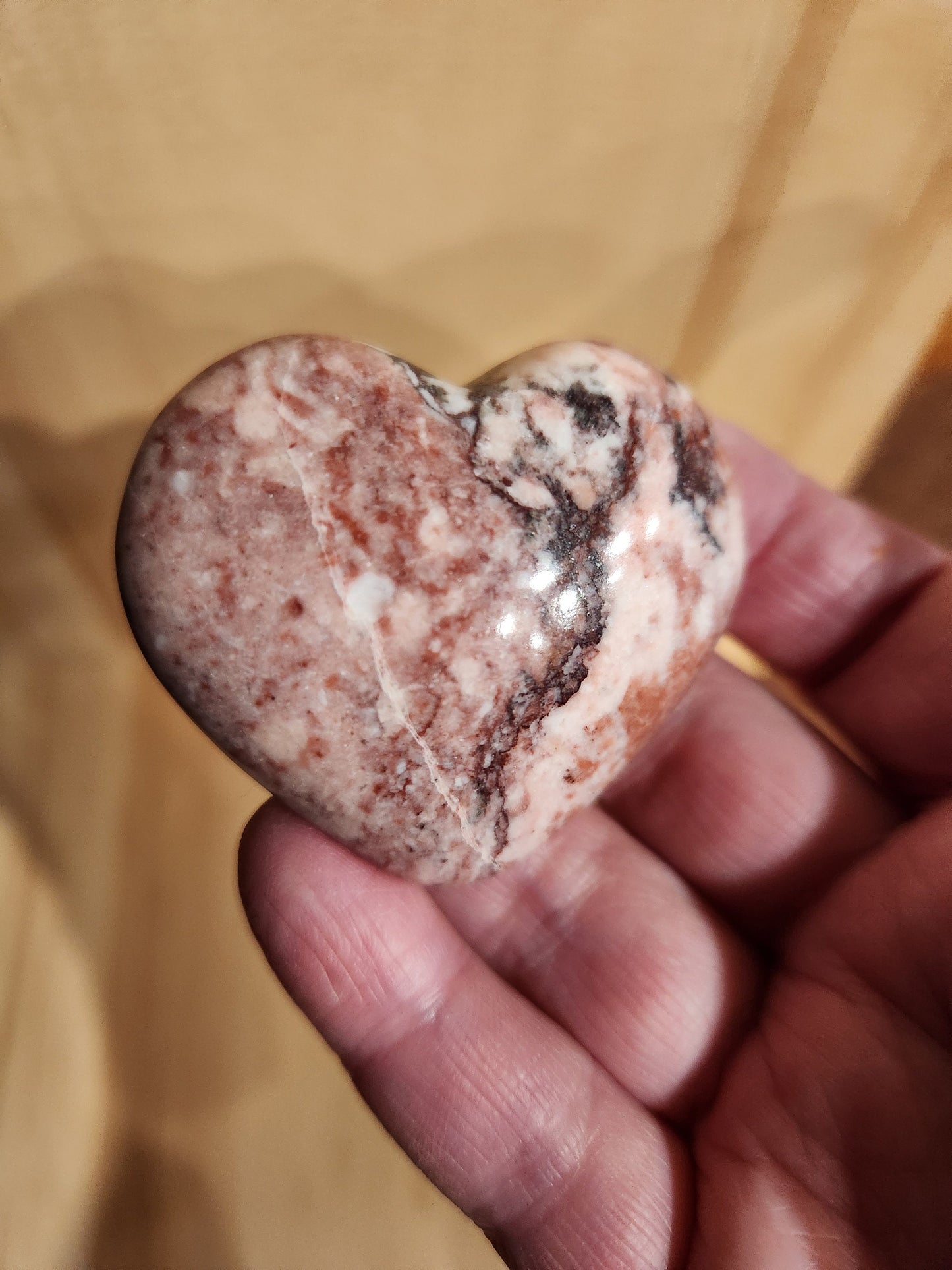 May include: A heart-shaped stone with pink, white, and brown marbling.